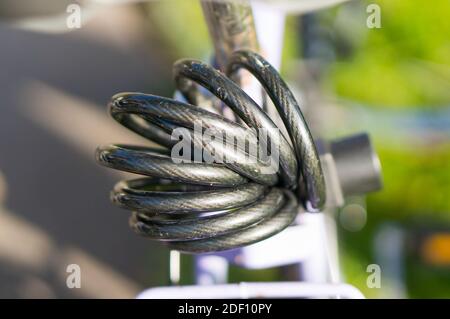 Una foto in primo piano di un lucchetto grigio per il cavo di una bicicletta Foto Stock