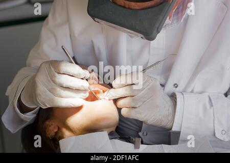 Dentista con guanti in lattice con strumenti ortodontici su pazienti di sesso femminile con bocca aperta. Cura orale, concetti di trattamento di clinica odontoiatrica Foto Stock