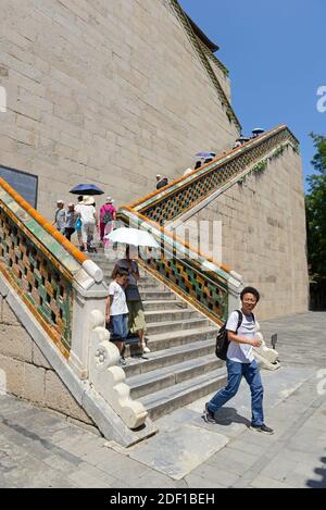 I visitatori scendono una scalinata di piastrelle gialle imperiali al Palazzo d'Estate a Pechino, Cina Foto Stock