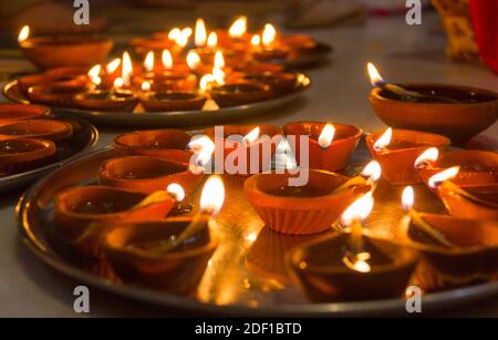 Accendendo candele e lampade di argilla su vassoi d'argento per Diwali Hindu Festival di luci a Mysore, Karnataka, India. Festa della famiglia a casa concetto Foto Stock