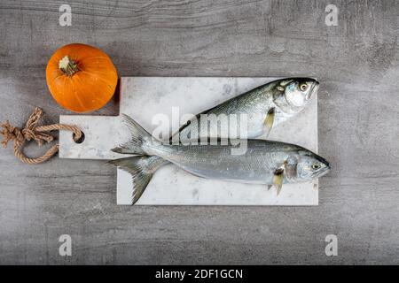 Bluefish grezzo. (Latino; Pomatomus Saltatrix). Pesce fresco con le verdure, condimento e limone, bluefish. Preparazione degli alimenti. Foto Stock