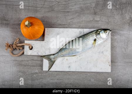 Bluefish grezzo. (Latino; Pomatomus Saltatrix). Pesce fresco con le verdure, condimento e limone, bluefish. Preparazione degli alimenti. Foto Stock