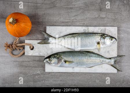 Bluefish grezzo. (Latino; Pomatomus Saltatrix). Pesce fresco con le verdure, condimento e limone, bluefish. Preparazione degli alimenti. Foto Stock