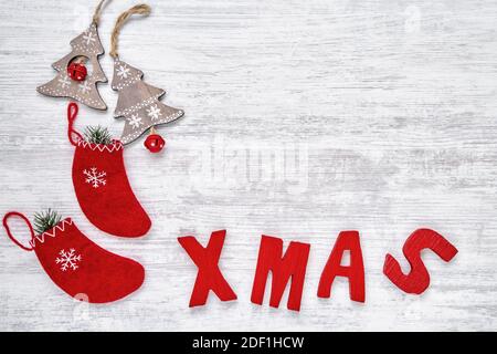 Backgroud di Natale con calze di Natale e ornamenti, lettere di legno rosso che formano la parola XMAS. Spazio di copia, vista dall'alto. Biglietto d'auguri di Natale Foto Stock