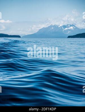 Una scia di boatâ€™s causa increspature e forme sull'acqua Superficie in Alaska Foto Stock