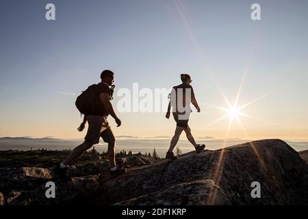 Due escursionisti raggiungono la cima della montagna nel Maine all'alba Foto Stock