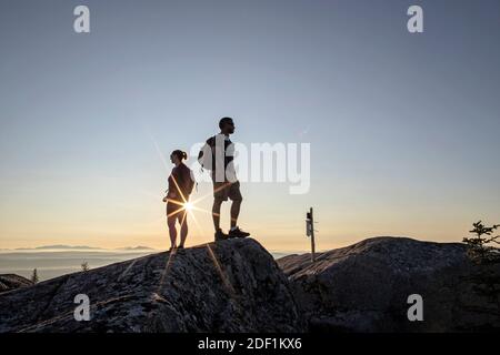 La giovane coppia adulta guarda la vista dalla cima, Moxie Bald, Maine Foto Stock