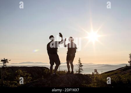 Due escursionisti alto cinque e celebrare raggiungere la cima della montagna, Maine Foto Stock