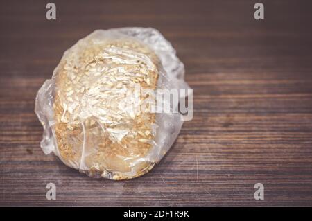 Un closeup di una pagnotta di pane ricoperta di grani avvolto in un sacchetto di plastica Foto Stock