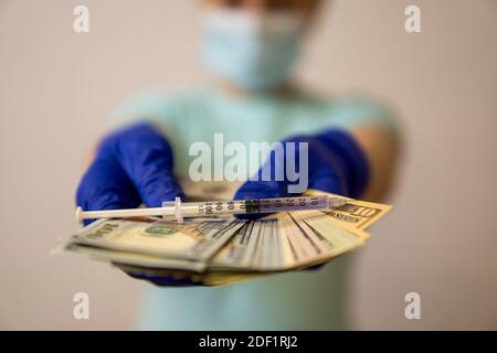 mani in guanti medici tenere il denaro su cui si trova la siringa... alta qualità Foto Stock