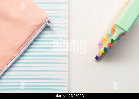 Penne color pastello, taccuino e custodia a matita da scuola su sfondo bianco Foto Stock