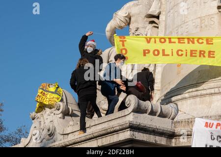 Parigi, Francia - 28 novembre 2020 : alla marcia contro la legge sulla sicurezza globale, un gruppo di persone che appendono bandiere in cima al Monumento al Rep Foto Stock