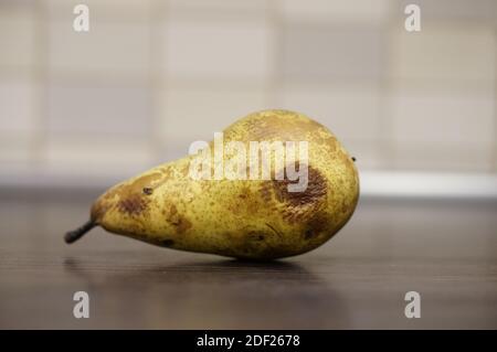 Un colpo di closeup di una pera gialla marcita su un tavolo di legno Foto Stock