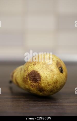 Un colpo di closeup di una pera gialla marcita su un tavolo di legno Foto Stock