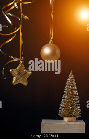 Albero d'inverno dorato con palle di Natale e luci scintillanti in decorazione xmas su sfondo nero. Composizione minimalista per le feste di Capodanno con copia Foto Stock