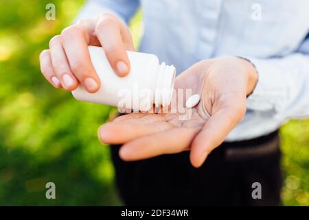 ragazza che tiene un vaso di pillole nelle sue mani, all'aperto Foto Stock