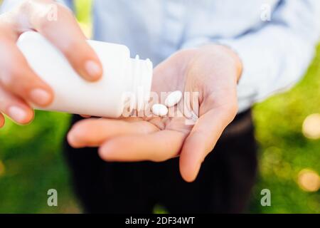 ragazza che tiene un vaso di pillole nelle sue mani, all'aperto Foto Stock