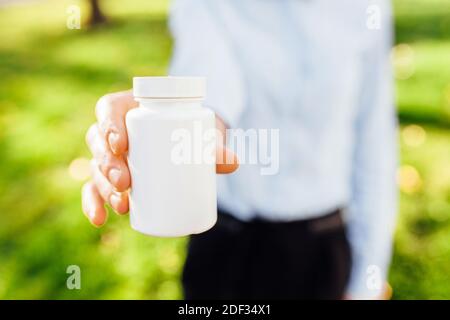 ragazza che tiene un vaso di pillole nelle sue mani, all'aperto Foto Stock