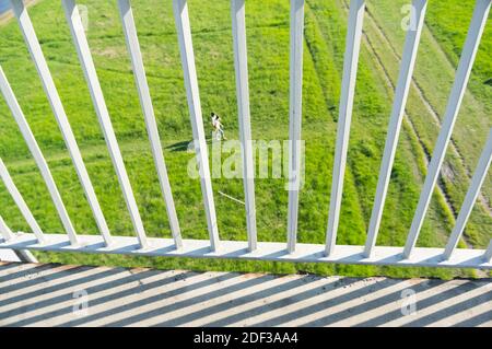 Una recinzione metallica con un campo verde e ombre Foto Stock