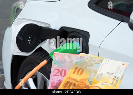 Un'auto elettrica e banconote in franchi svizzeri Foto Stock