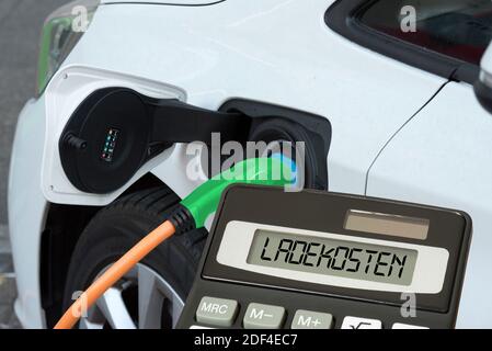Un'auto elettrica, una calcolatrice e si carica per la ricarica Foto Stock