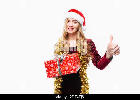Bella ragazza nel cappello di Babbo Natale, è felice circa il regalo di Natale, nelle sue mani è un regalo. Su sfondo bianco Foto Stock
