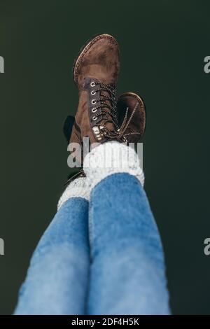 Primo piano sui piedi della ragazza che indossa stivali marroni e jeans blu con calze lunghe. Concetto di stile di vita creativo Foto Stock