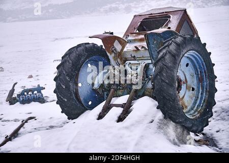 Parti smontate del vecchio trattore come rifiuti e inquinamento su un ghiacciaio di montagna; concetto di problemi ambientali Foto Stock