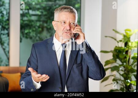 Imprenditore maturo che chiama al telefono Foto Stock