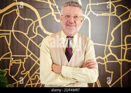 Ritratto di allegro imprenditore senior in occhiali pieghevoli e braccia sorridendo alla macchina fotografica Foto Stock