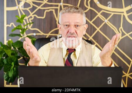 Imprenditore di mezza età confuso che ha videochiamata con colleghi o aziende partner Foto Stock