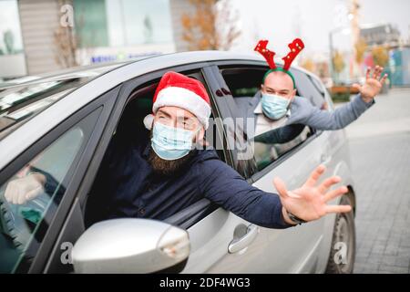 Amici che indossano una maschera protettiva per il viso in auto. Vacanze durante l'epidemia. Foto Stock