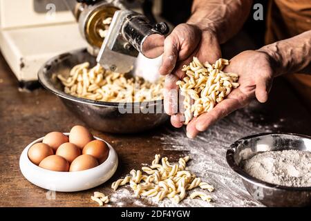 Forme di pasta gemelli appena fatte con uova e farina trattenute nelle mani dello chef. Foto Stock