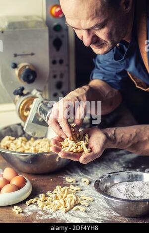 Pasta italiana appena fatta a forma ritorta nelle mani di un piccolo produttore. Foto Stock