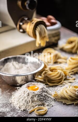 Farina, uova e pasta per la produzione di fettuccine italiane fresche. Foto Stock