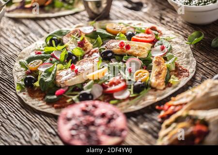 Tortilla vegetariane all'aperto con insalata, raddish, pomodori a base di carne, olive, melograno e haloumi alla griglia. Foto Stock