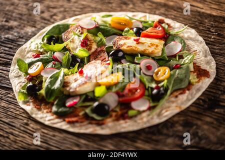 Tortilla vegetariane all'aperto con insalata, raddish, pomodori a base di carne, olive, melograno e haloumi alla griglia. Foto Stock