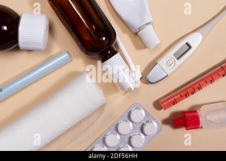 Bendaggio, flaconi di medicina, pillole e un termometro su uno sfondo beige chiaro. Foto per medicina e farmacia. Foto Stock