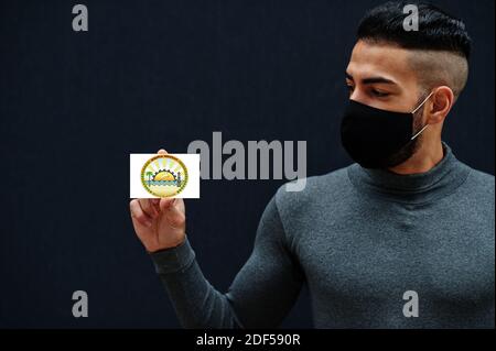 Uomo egiziano in tleneck grigio e maschera di protezione viso nero mostra Matruh bandiera sfondo isolato. Governatorati di Egitto coronavirus concetto. Foto Stock