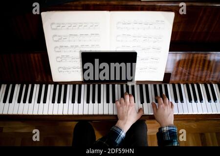 Insegnante di suonare il pianoforte durante le lezioni online utilizzando un tablet a. comunicare con gli studenti Foto Stock