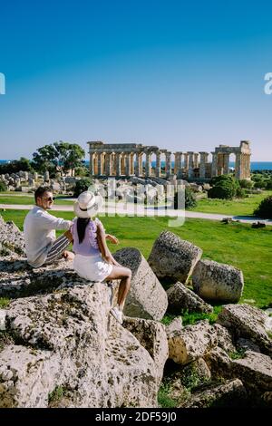 Una coppia visita templi greci a Selinunte durante le vacanze, vista sul mare e rovine di colonne greche nel Parco Archeologico Selinunte Sicilia Italia Foto Stock