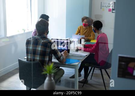 Diversi gruppi di colleghi che indossano maschere in ufficio Foto Stock