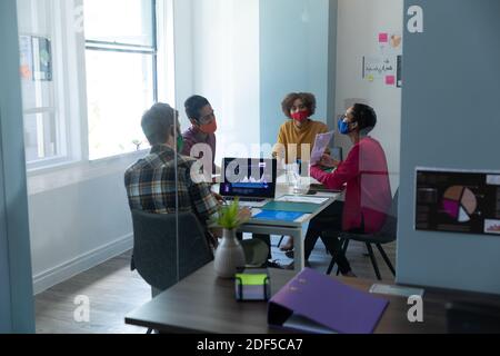 Diversi gruppi di colleghi che indossano maschere in ufficio Foto Stock