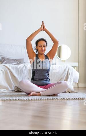 Pratica di yoga a casa. Donna afroamericana meditando mentre fa yoga. Foto verticale. Foto Stock