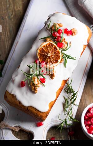 Torta di frutta spolverata con glassa, noci, melograno di noccioli e primo piano di arancio secco. Natale e inverno torta fatta in casa Foto Stock