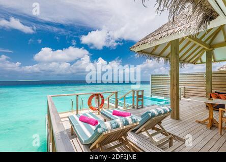 Fantastica villa sull'acqua, terrazza con sedie a sdraio sotto l'ombrellone, lussuoso hotel con piscina e splendida vista sull'oceano. Bella spa o benessere Foto Stock