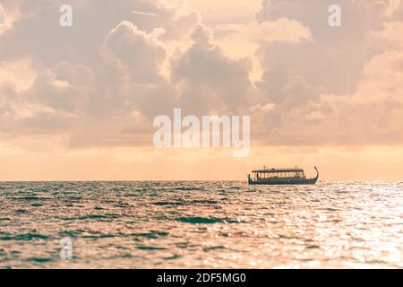 Maldive crociera al tramonto con barca Dhoni nelle isole Maldive. Tramonto tropicale sul mare, mare. Persone che si godono il tramonto e alla ricerca di vita marina Foto Stock