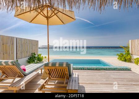 Lussuoso resort sulla spiaggia. Piscina rilassante e sedie a sdraio sotto l'ombrellone. Estate isola viaggi e vacanze, mare. Acqua villa Maldive Foto Stock