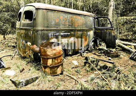 Abbandonata auto arrugginita e barile a sinistra nella foresta. Francia. Foto Stock