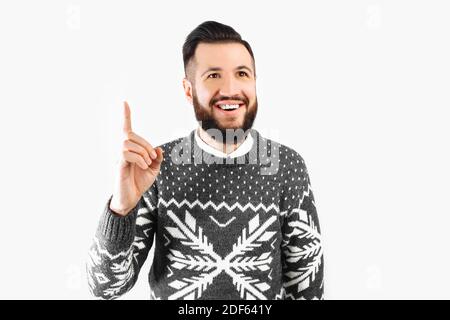 Un'immagine di un uomo sorridente che ha un'idea. Un bel ragazzo bearded in un maglione appena venuto in su con un pensiero grande. Su sfondo bianco Foto Stock